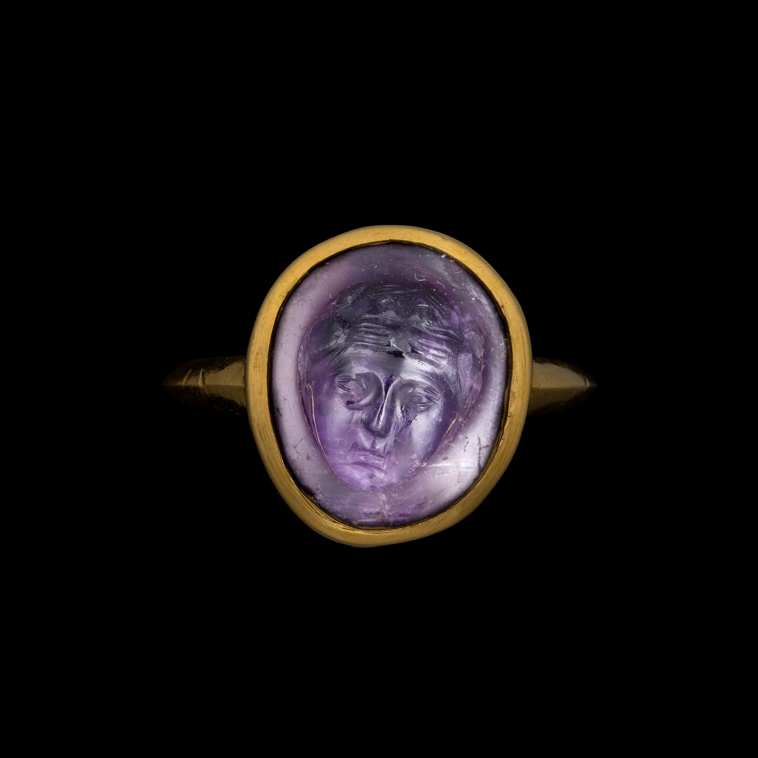 A gold ring set with a rare Roman amethyst cameo. Mask of Bacchus.
